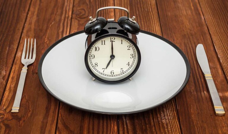 Un plato blanco vacío con un reloj encima y dos cubiertos en los laterales